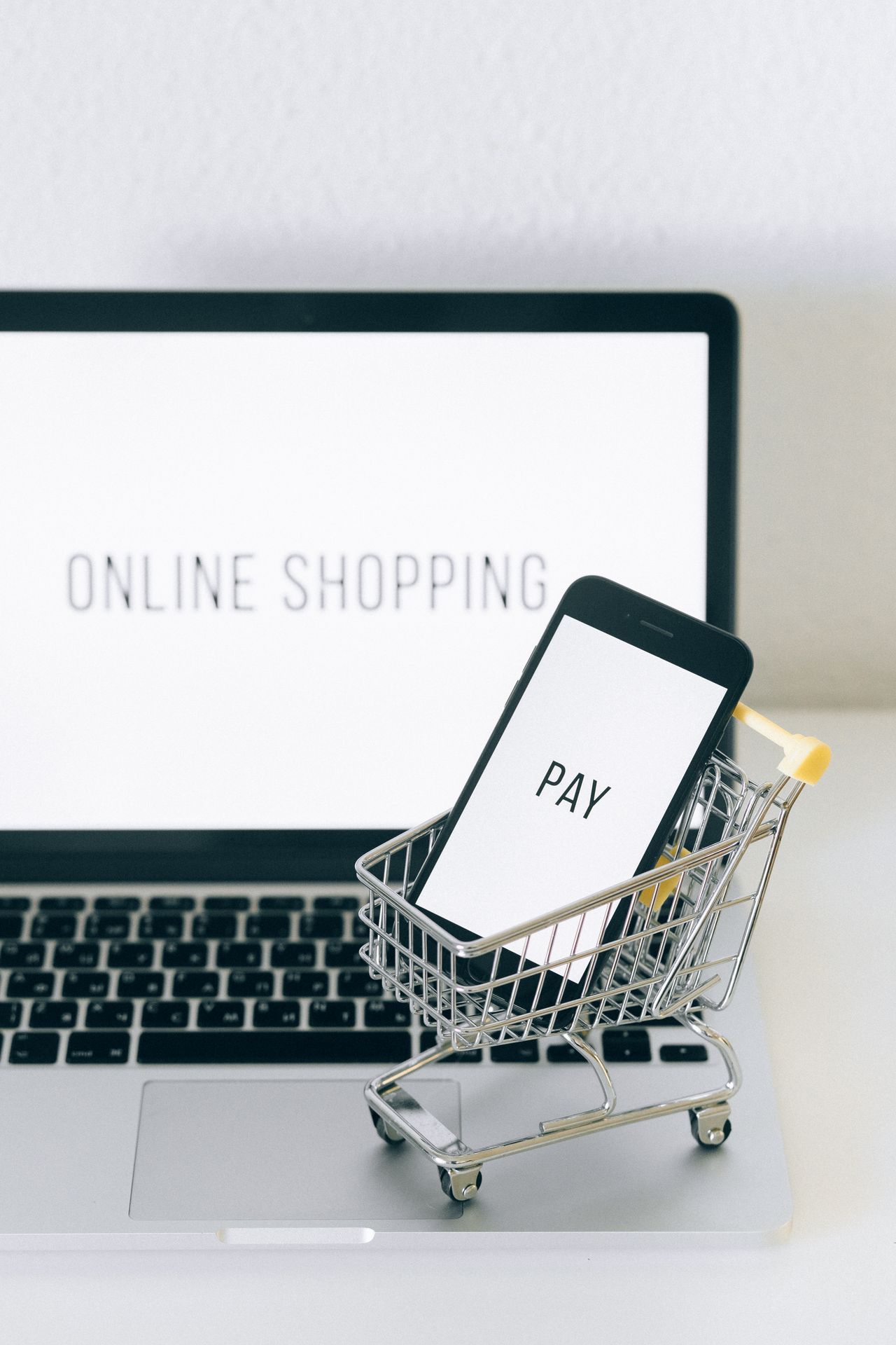 Điện thoại trong giỏ hàng mô hình đặt trước laptop hiển thị mua sắm trực tuyến