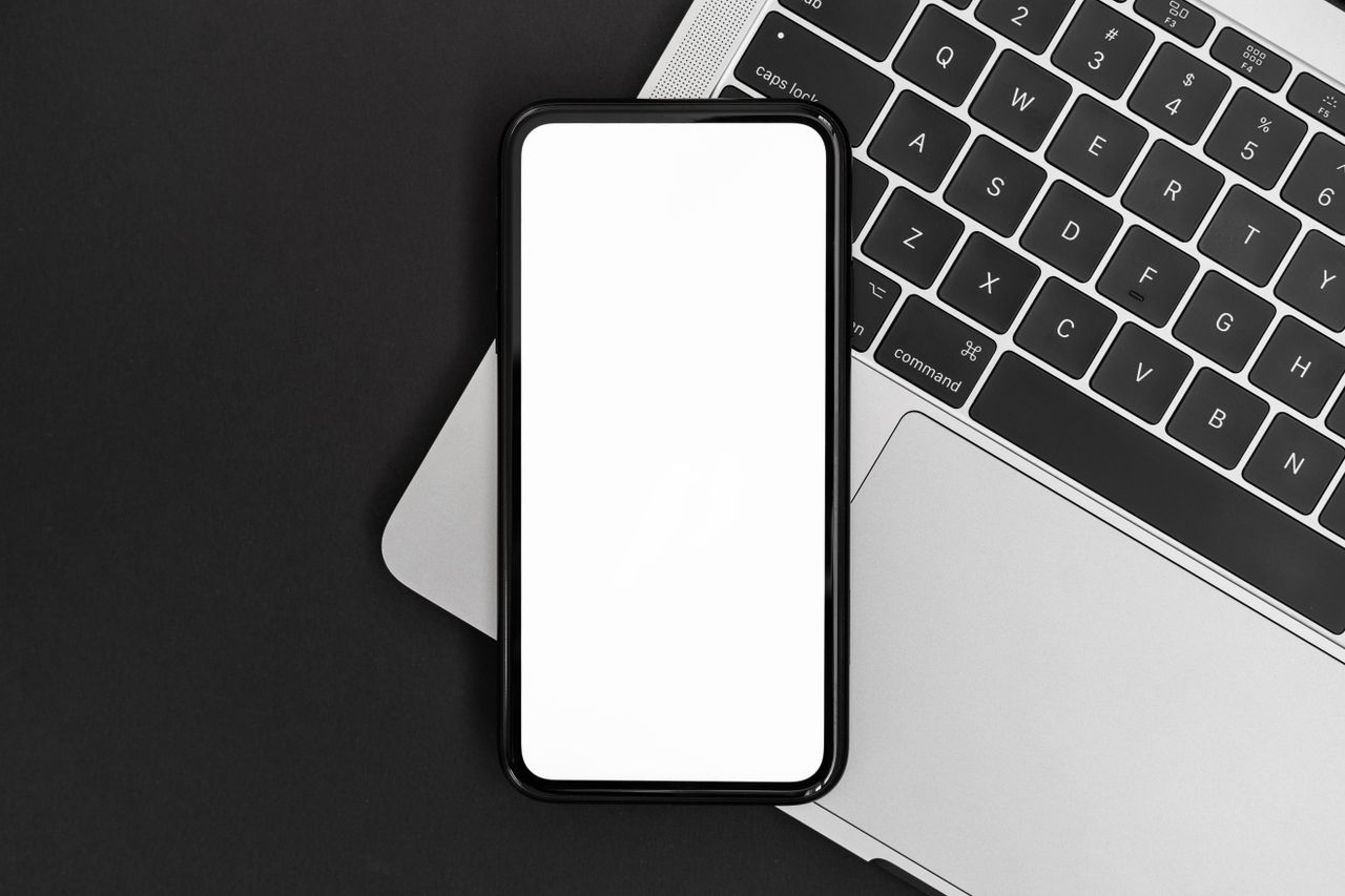 Điện thoại và laptop đặt cạnh nhau trên bàn