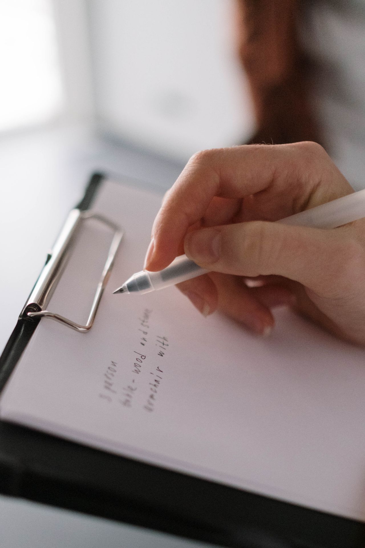 Người đang viết ghi chú lên bảng kẹp giấy