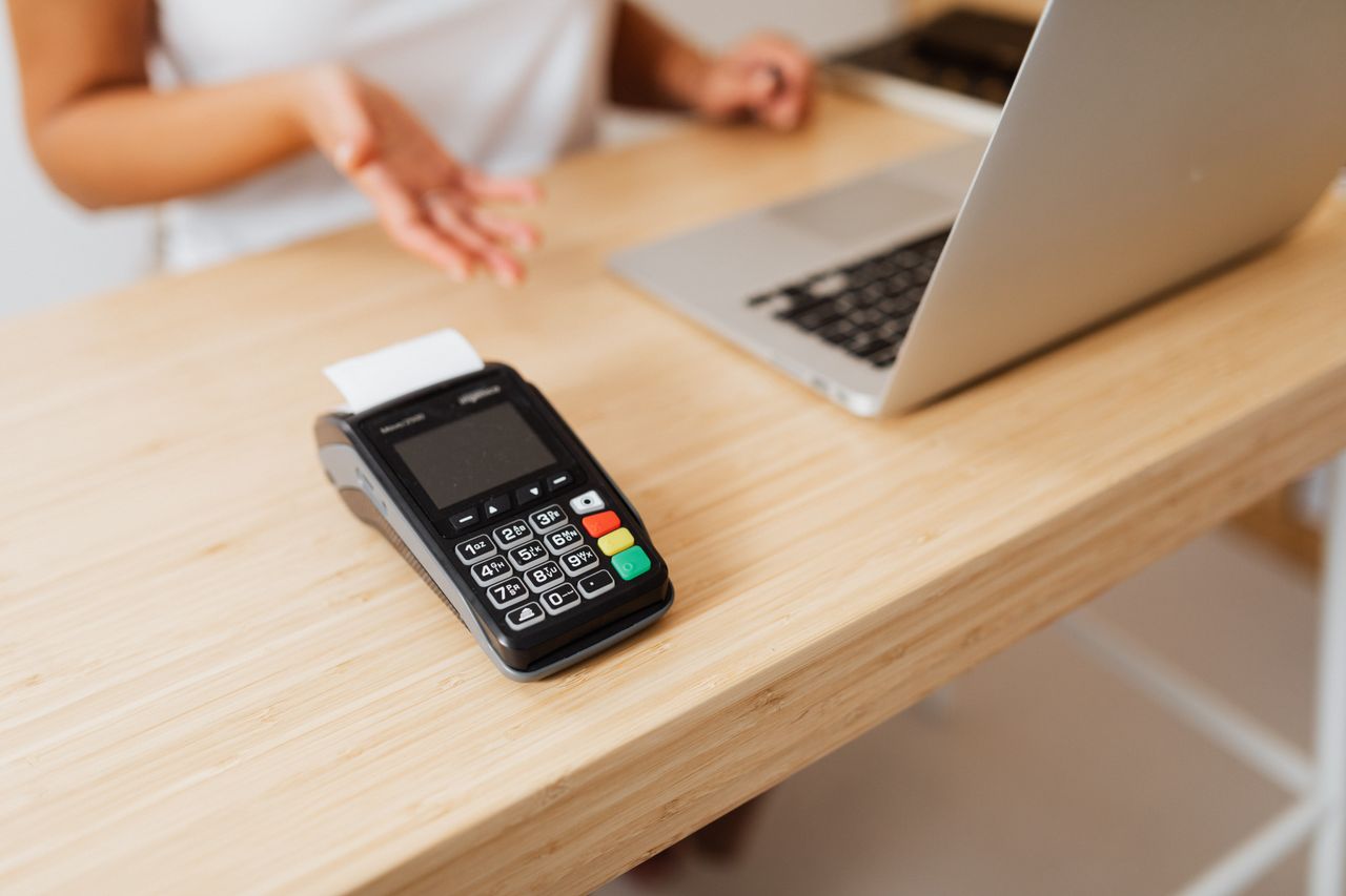 Máy thanh toán thẻ cạnh máy tính xách tay trên bàn gỗ