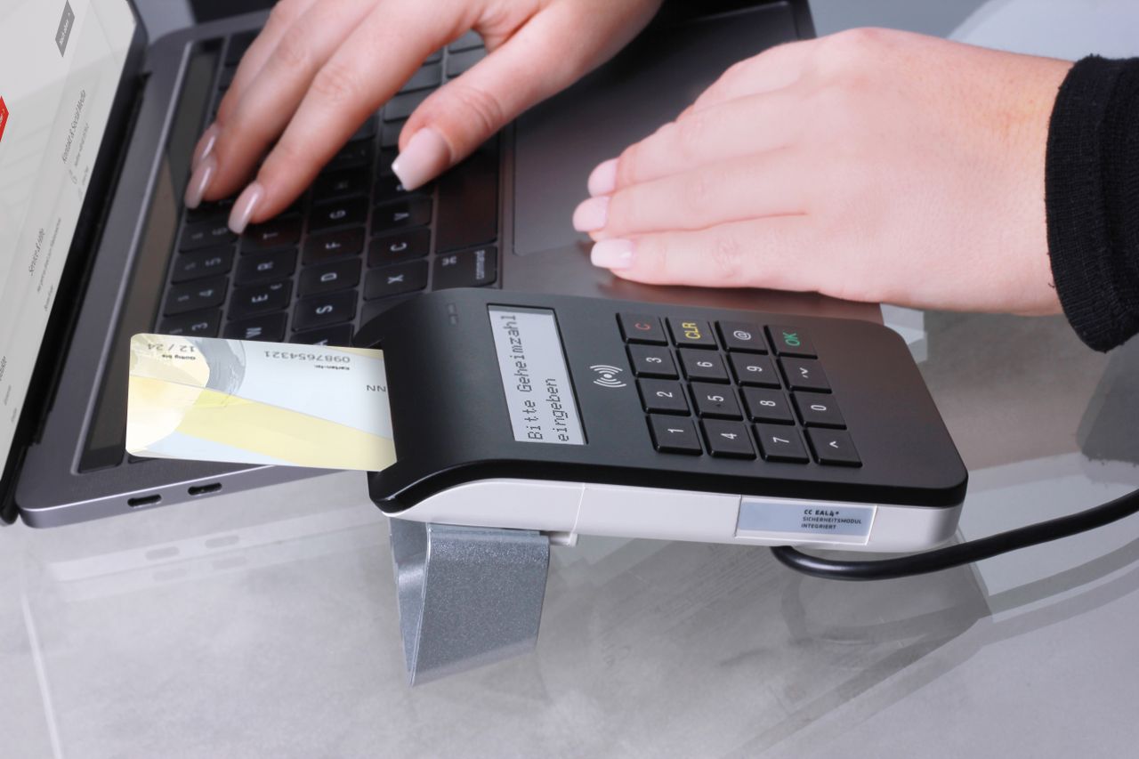 Bàn tay dùng thẻ trên máy thanh toán cạnh máy tính xách tay