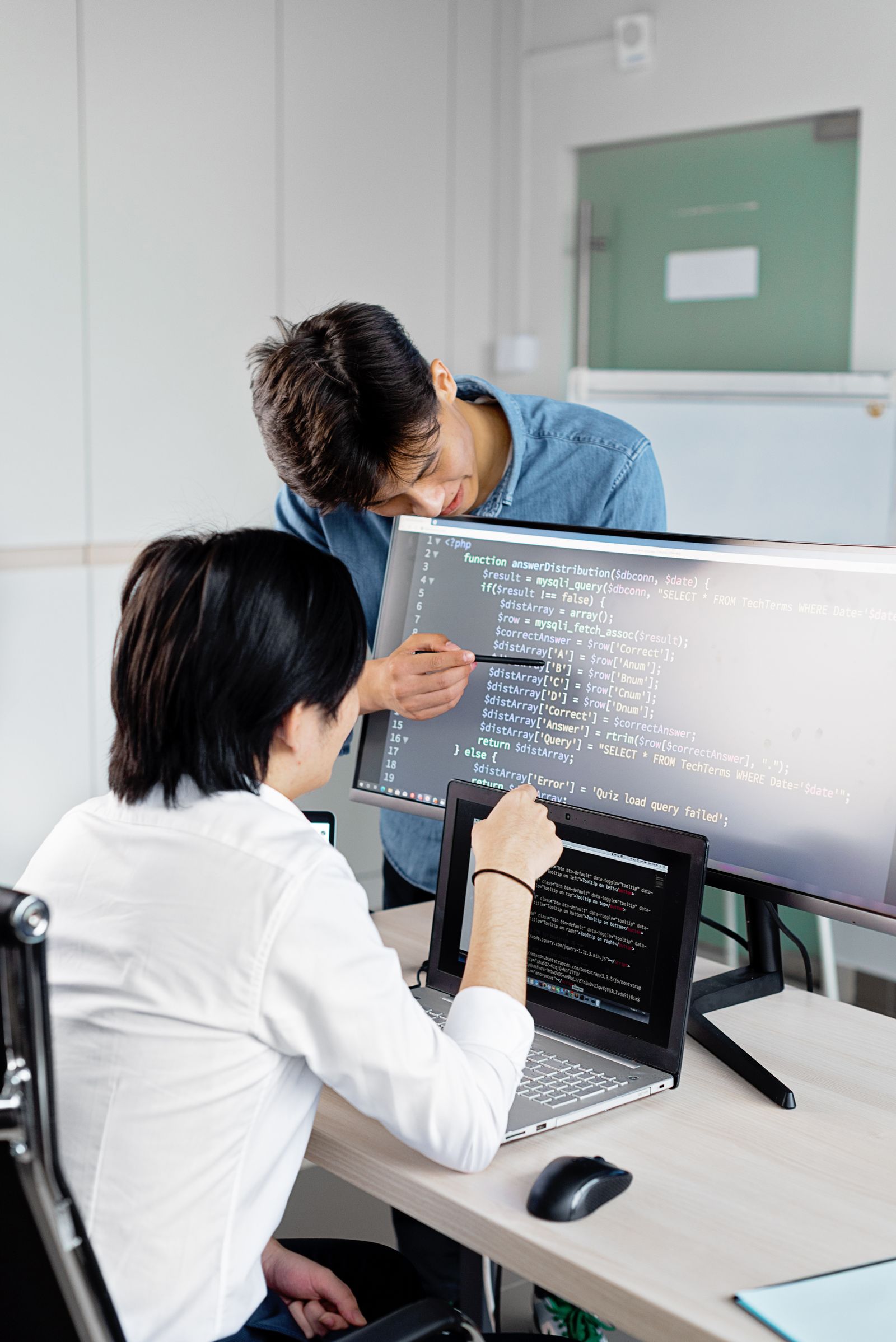 Two developers reviewing code together on a monitor
